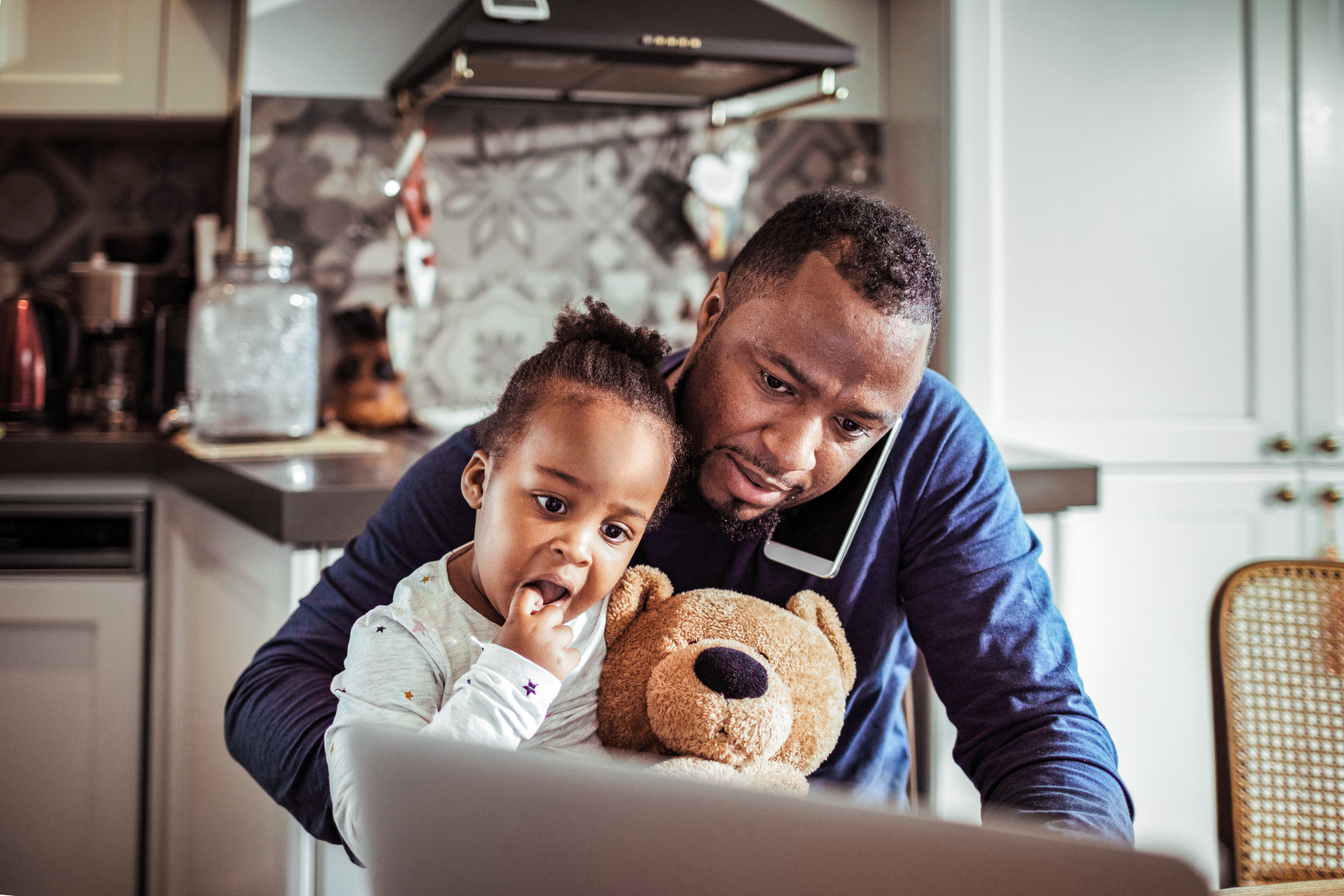 A father holding his daughter while on a call