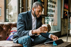 A man on his tablet with a coffee in hand