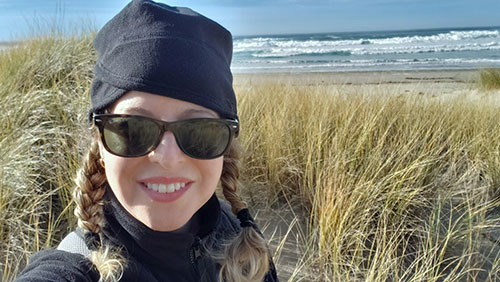 A selfie of Nichole with the beach behind her